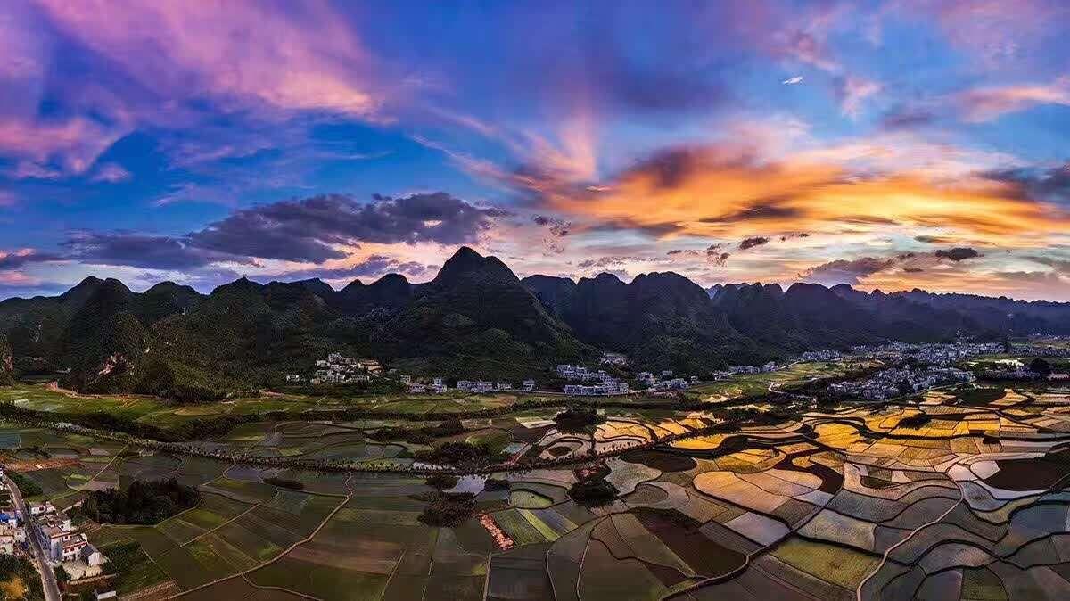 Deep pink and purple sunset sky over the silhouetted karst peaks and fields of Wanfenglin