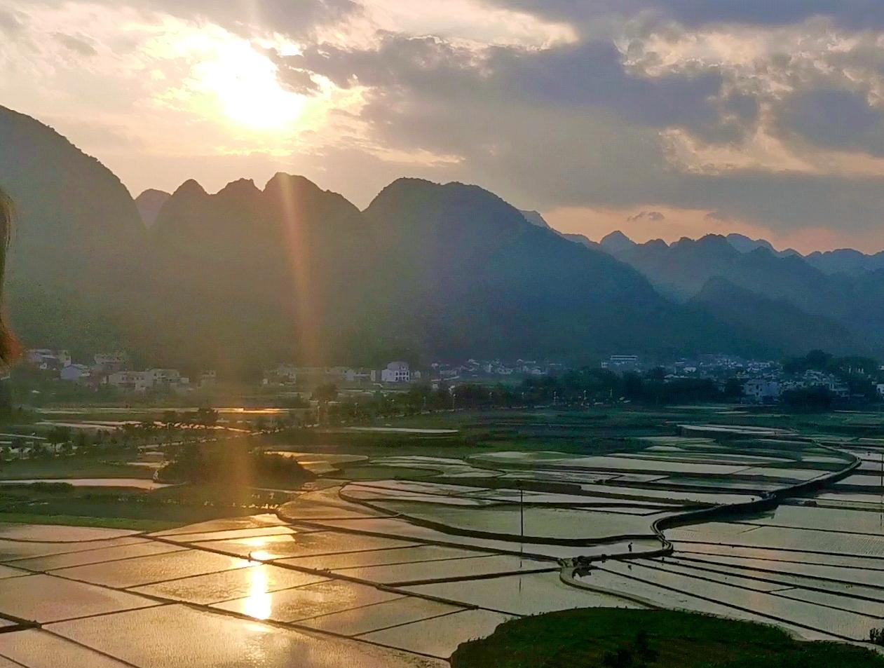 Sunrise light breaking over Wanfenglin karst peaks and reflecting in flooded rice paddies